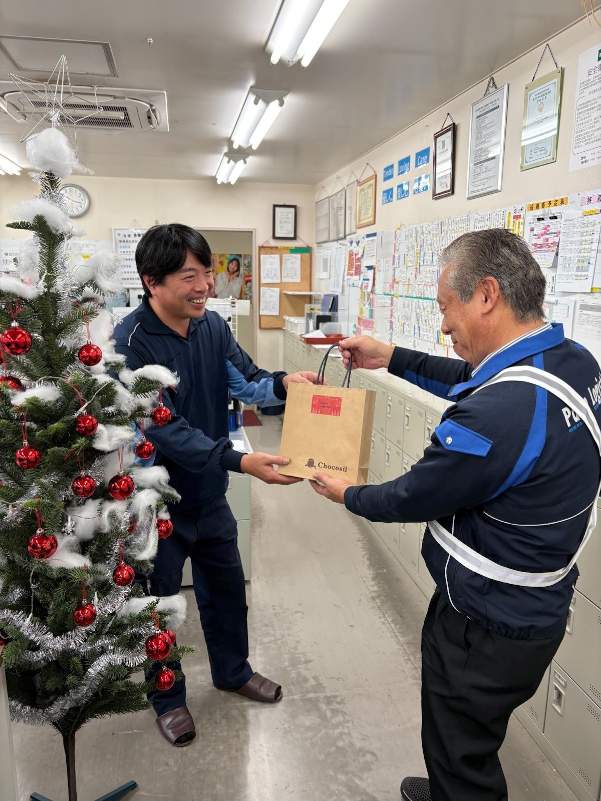 営業所長㊨からチョコレートを受け取る社員