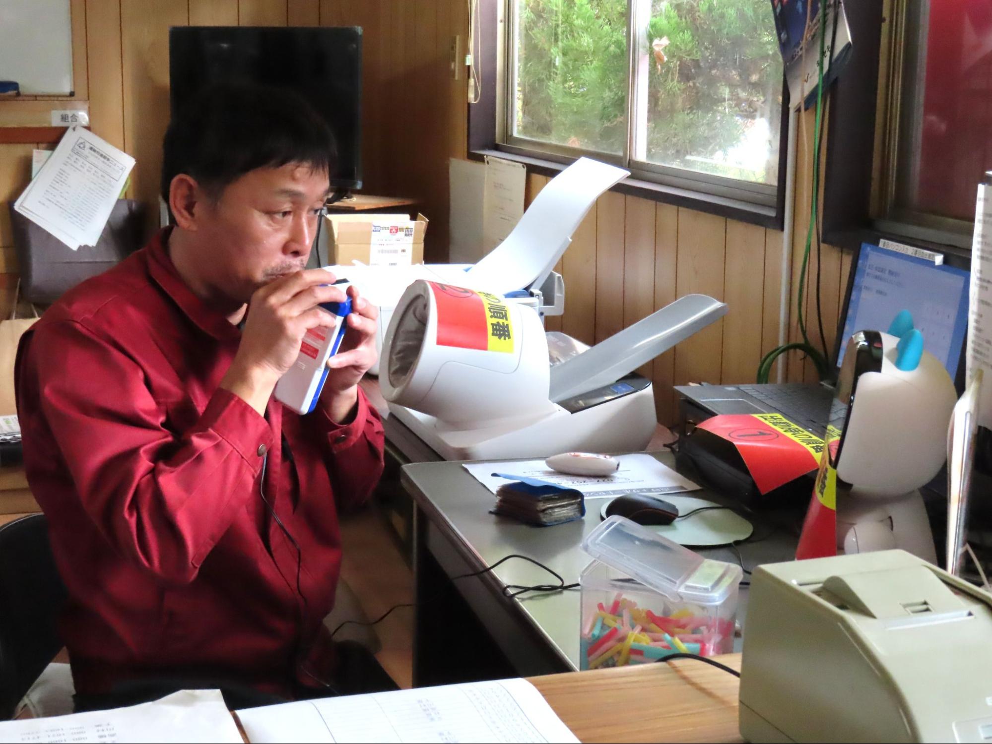 ロボットの指示によりアルコールチェックを行うドライバー