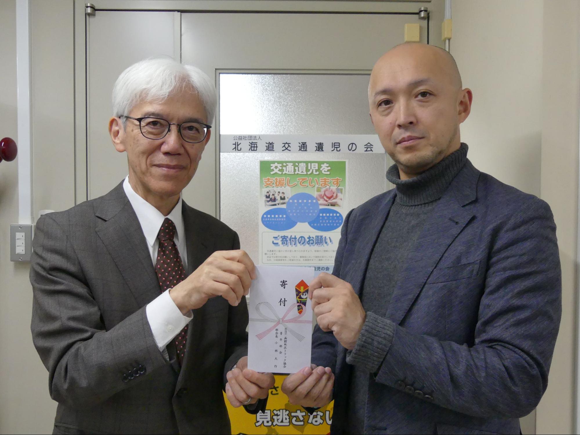 寄付金を持つ小林部会長㊨と遺児の会の吉田専務