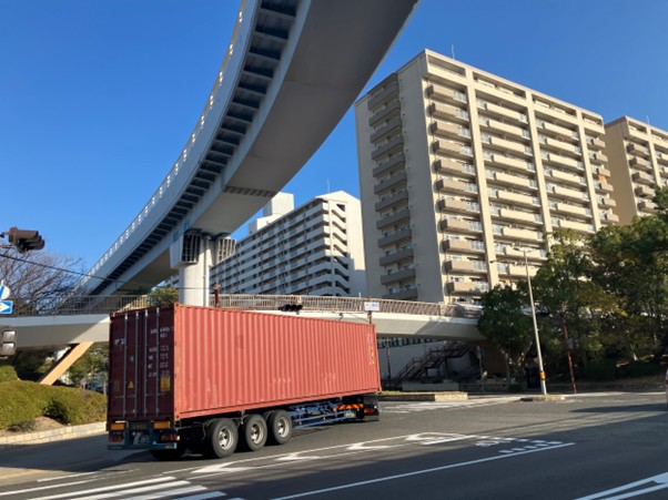 マンション前の道を通る海コン車両（12月16日）