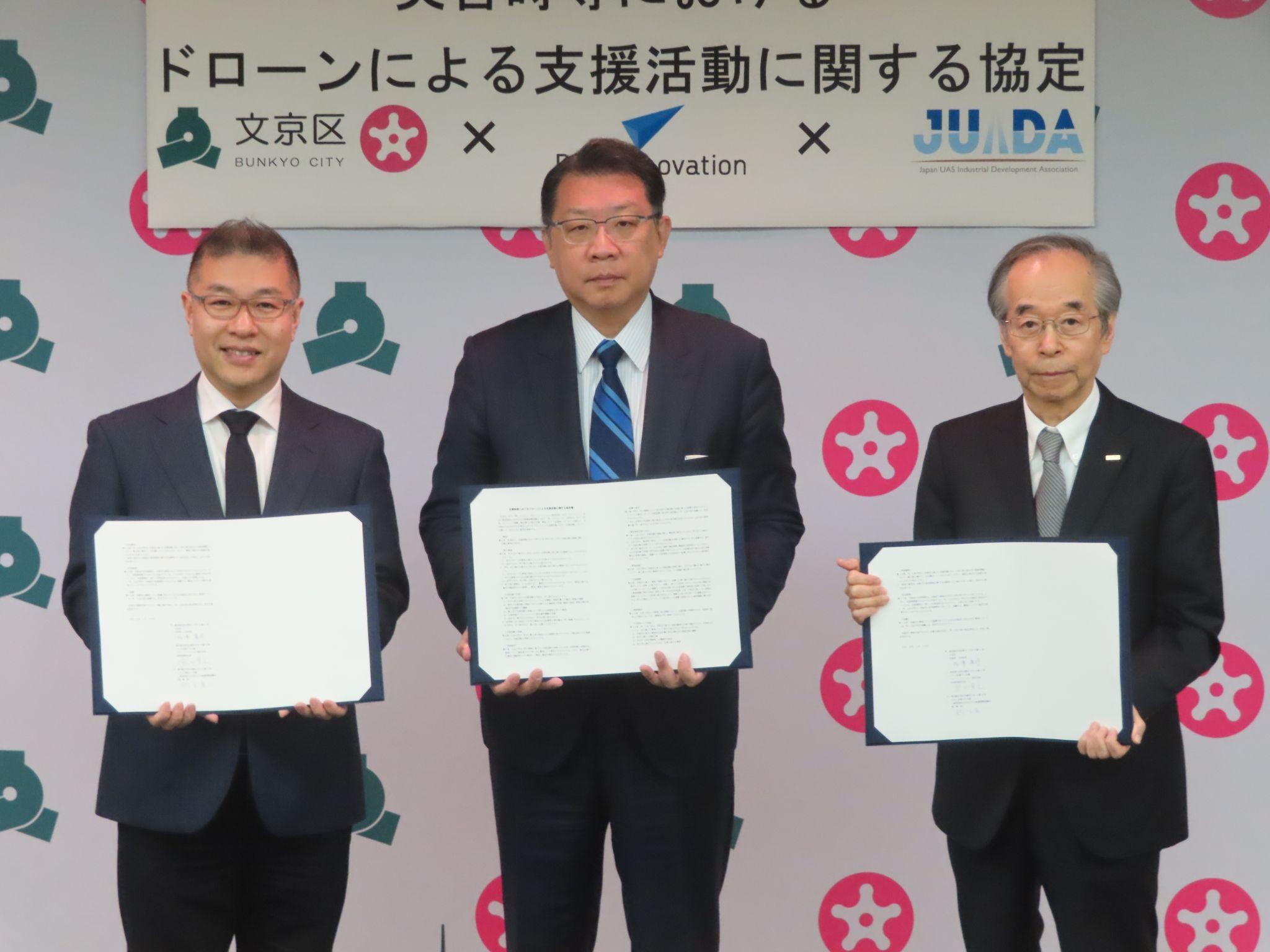 実効性の高い応急復旧活動を行うのが目的（左から締結書を手に熊田BI社長、成澤区長、鈴木JUIDA理事長）