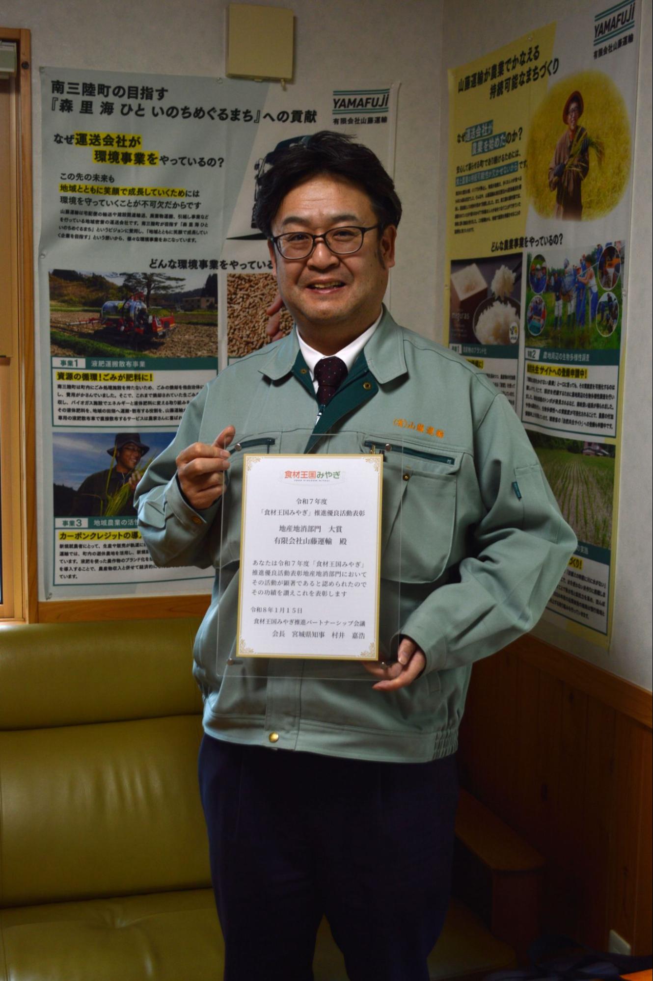 表彰状を手にする佐藤社長
