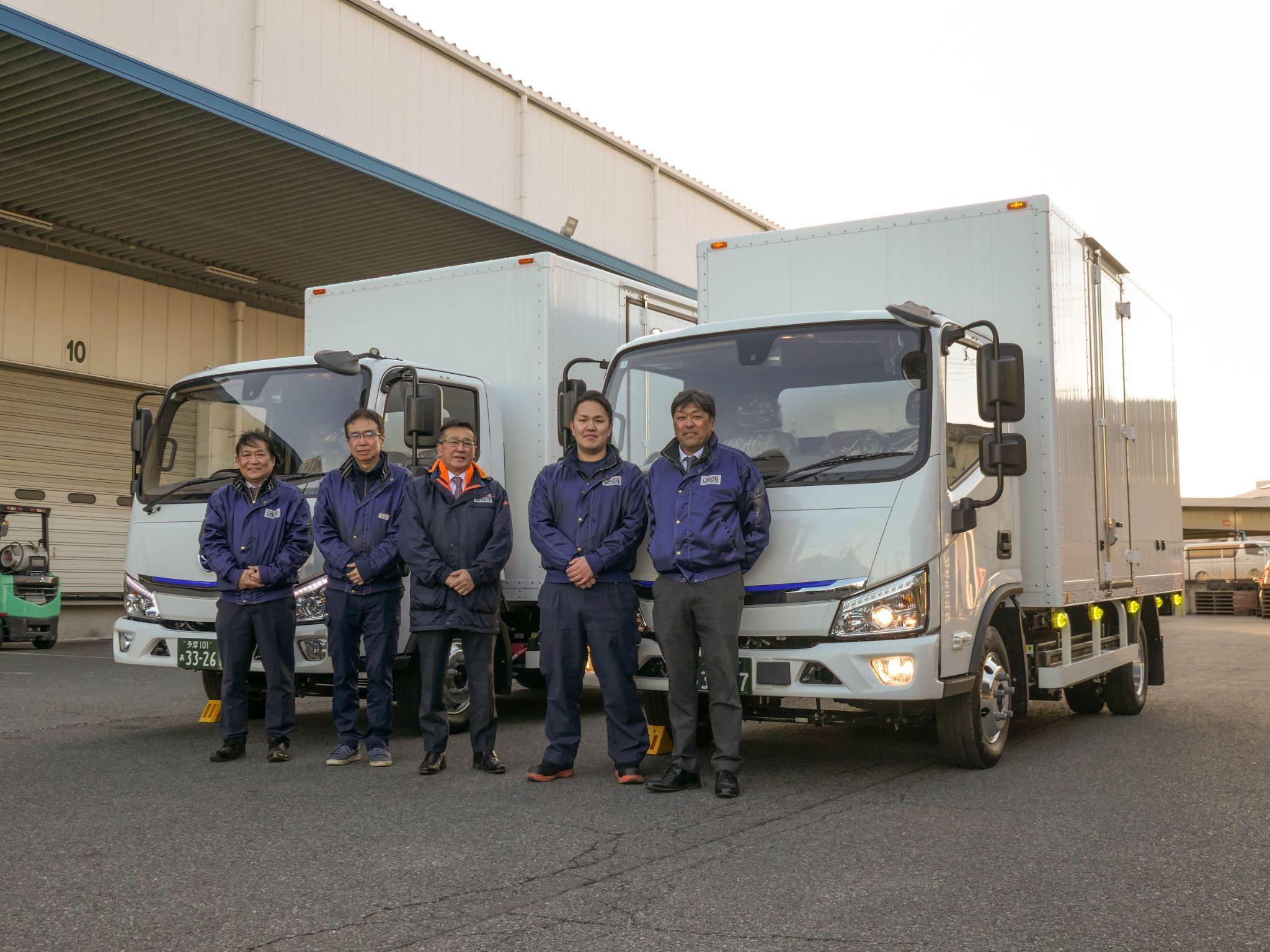 導入したトラックを背に川﨑社長（中央）と担当ドライバー