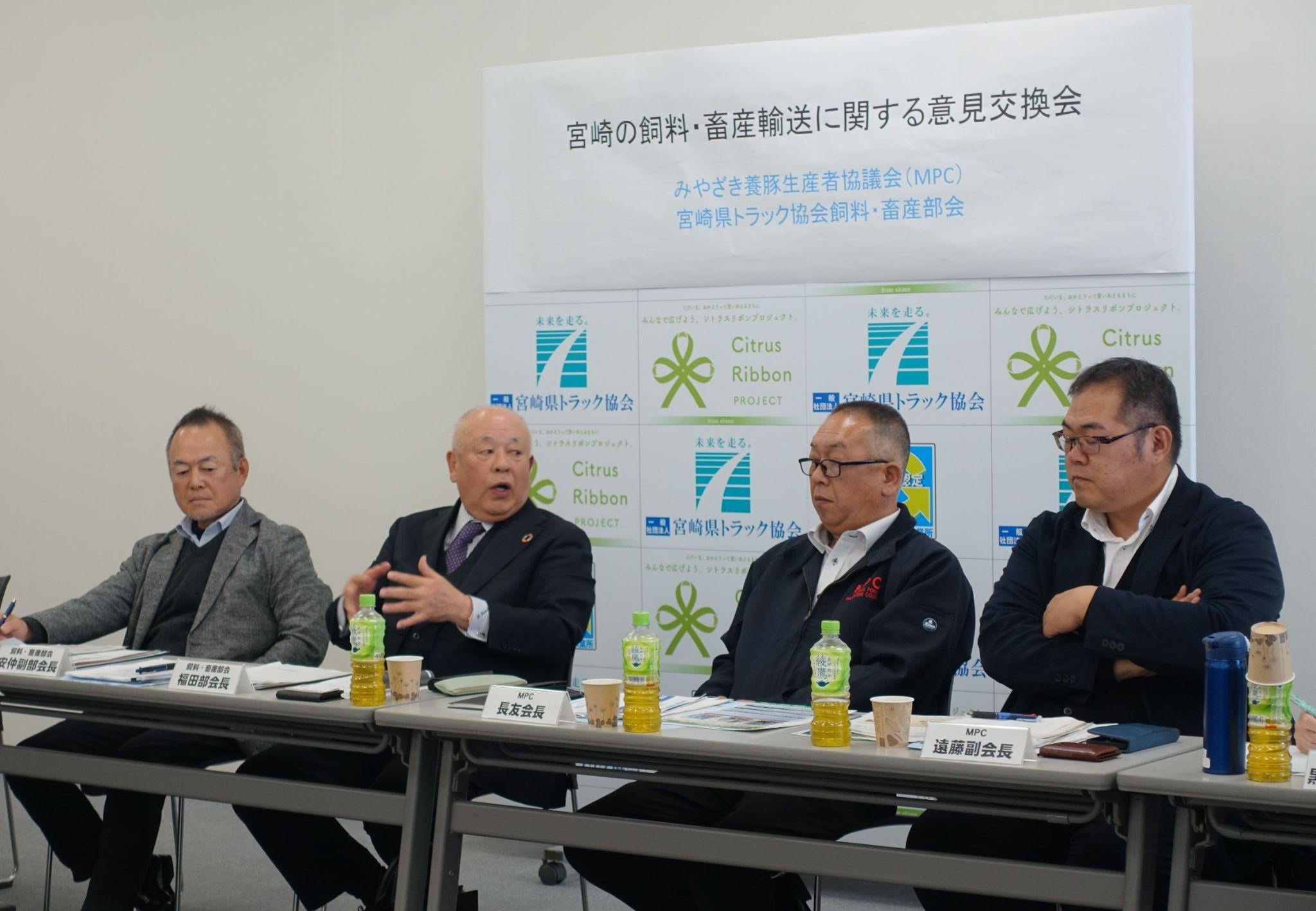 タンク下のひもを引っ張ることでふたを開閉できる装置の重要性などについて議論する（左から）宮ト協飼料畜産部会の安仲利明副部会長、福田部会長、MPCの長友会長、遠藤太郎副会長