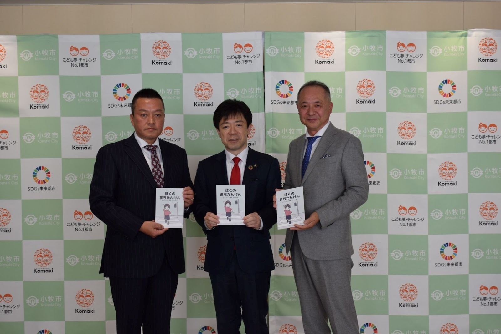 絵本を手に（右から）丸川支部長、山下市長、西影篤範小牧部会長