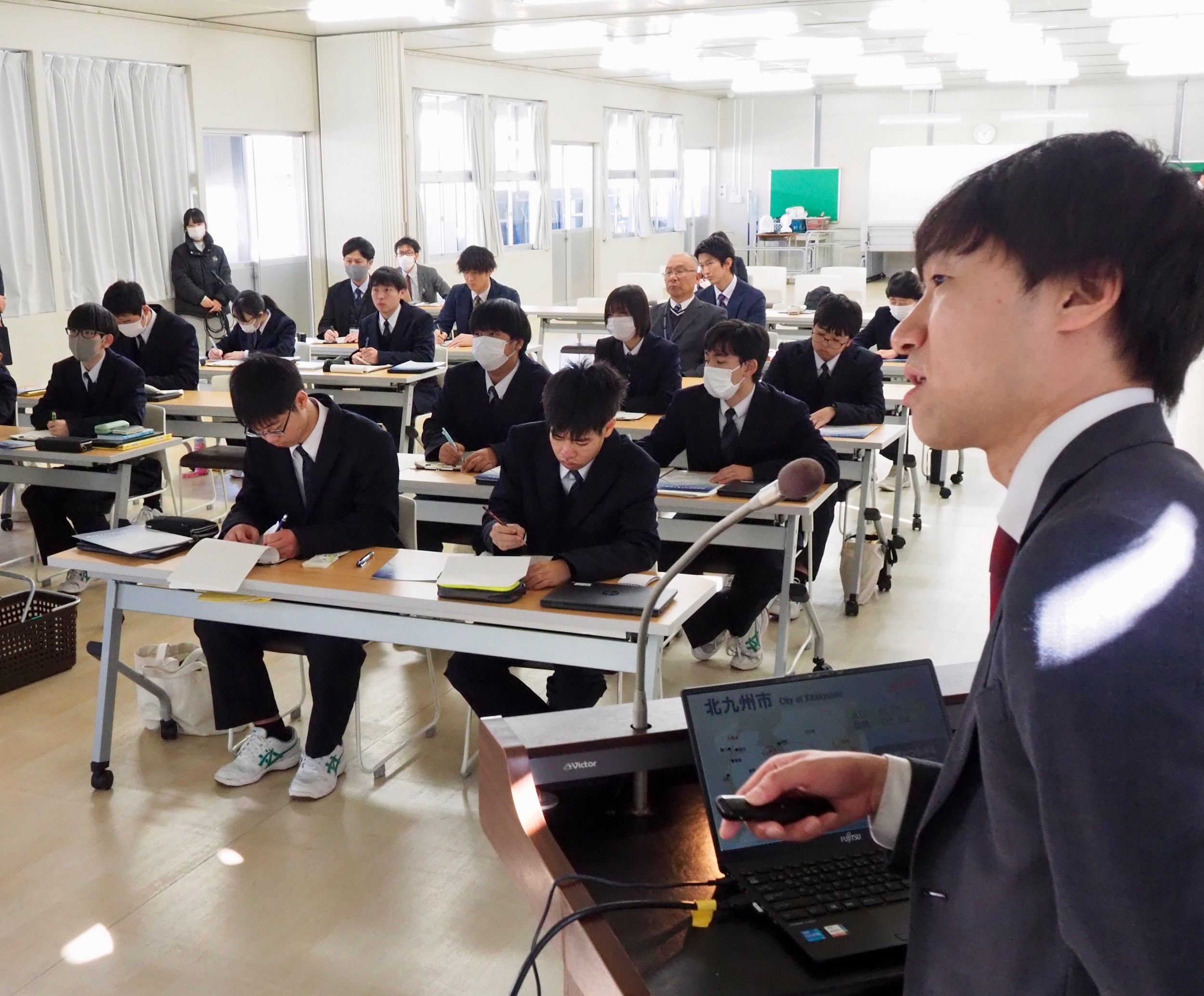 市職員㊨の講話で北九州市の物流インフラの歴史や種類を学ぶ生徒