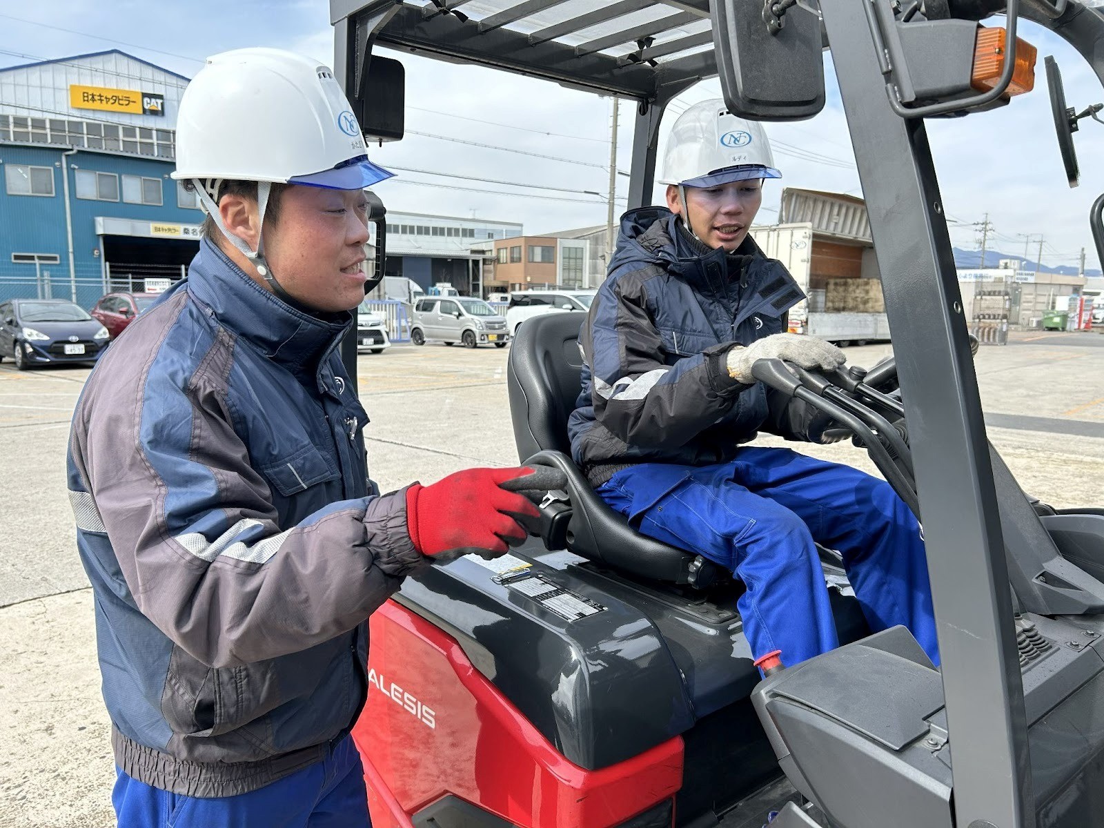 技能実習生のルディさん㊨にリフトの運転方法を教える教育課の片桐氏