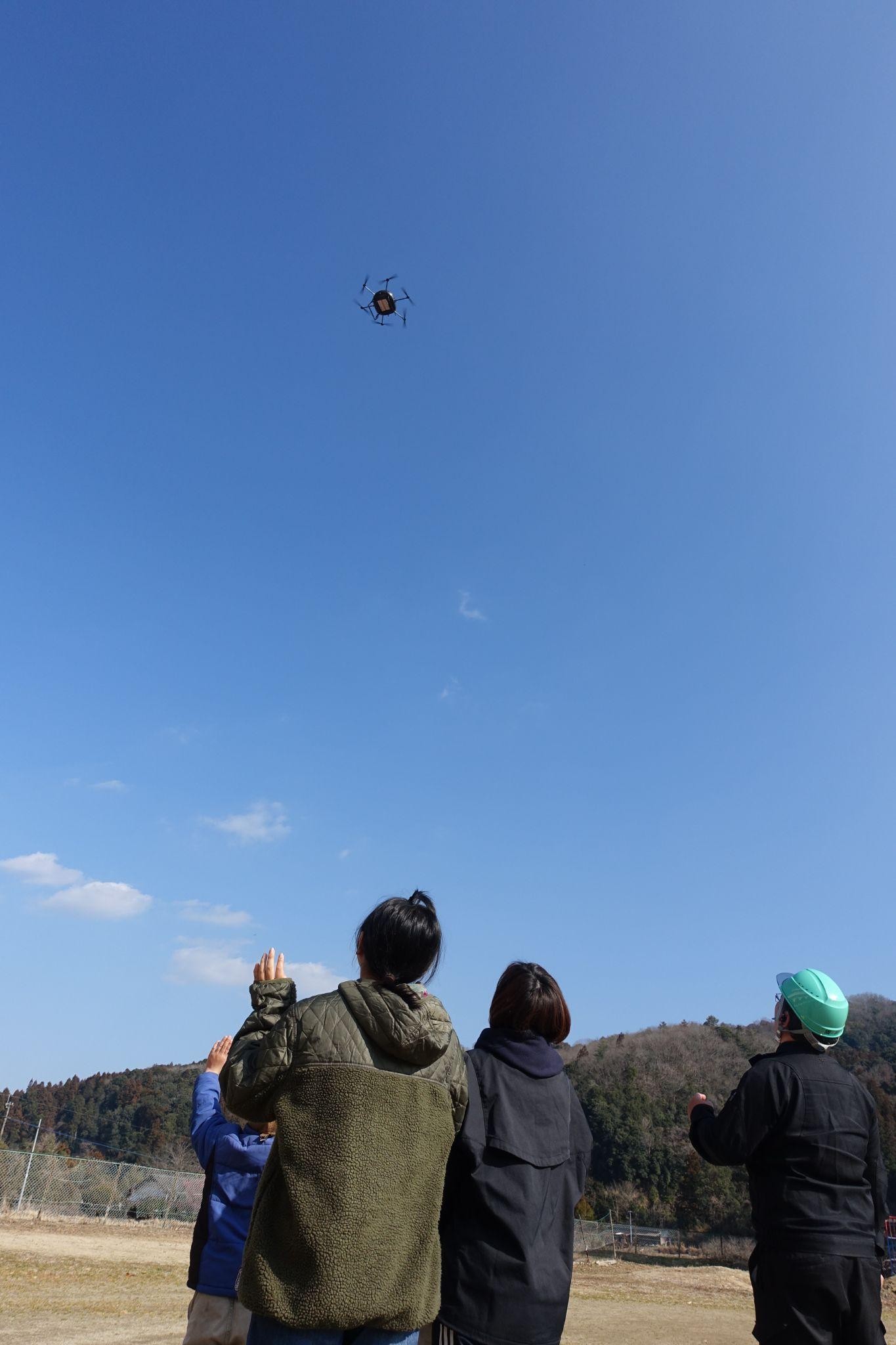 ドローンに手を振り着陸を見守る児童ら