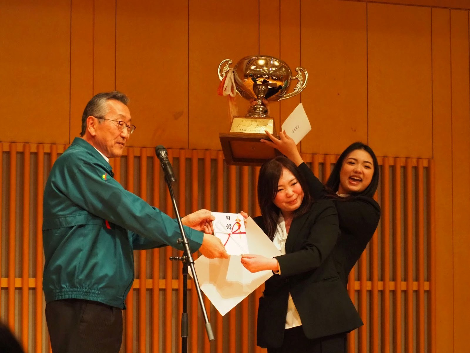 最優秀賞受賞チームにトロフィーを手渡す佐藤社長㊧