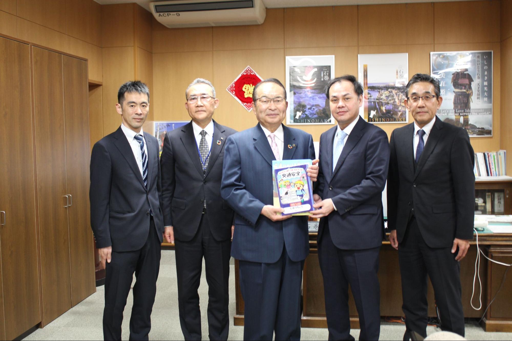 寄贈した文具を手に齋藤市長（中央）と青年部の佐藤部長（右隣）