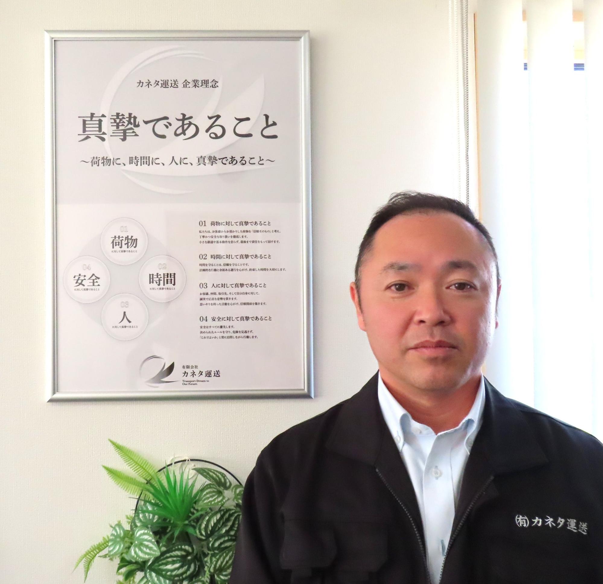 企業理念の前で金田社長