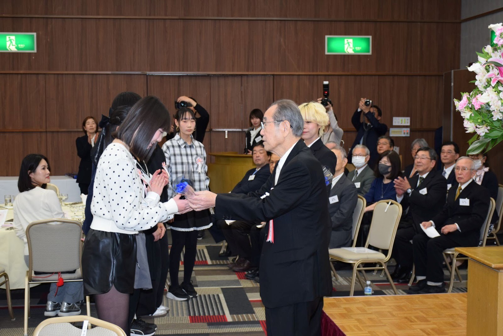 卒業する遺児に青いバラを贈る吉野会長（手前右）