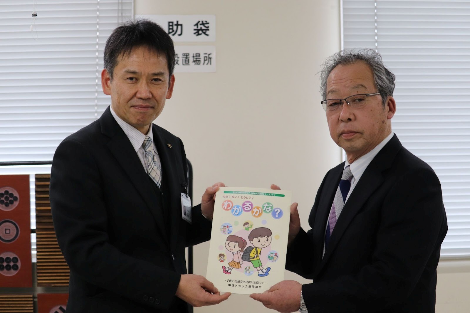 ワークブックを持つ丸山理事長㊨と市教委の曽根原教育長