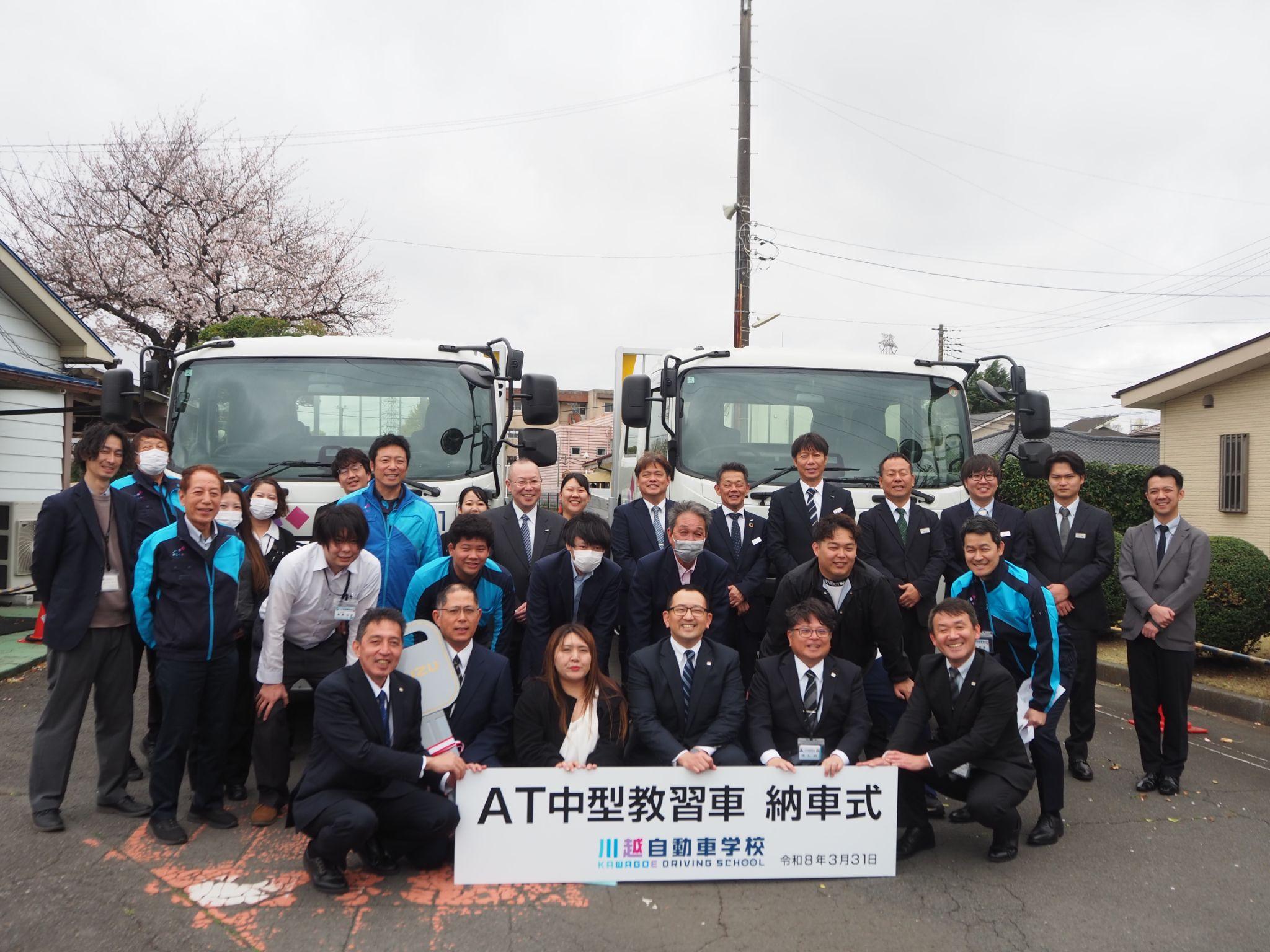 納車した中型ATトラックと横塚社長（最前列右から3人目）ら