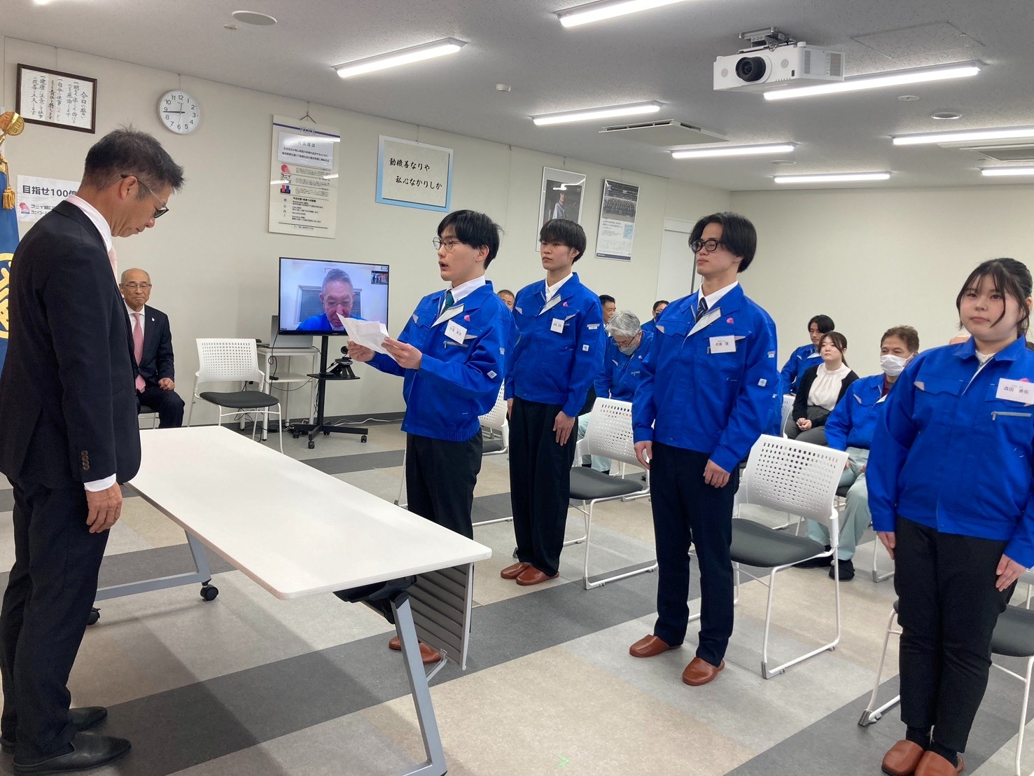 藤尾社長（左端）を前に決意表明する新入社員の大浦さん