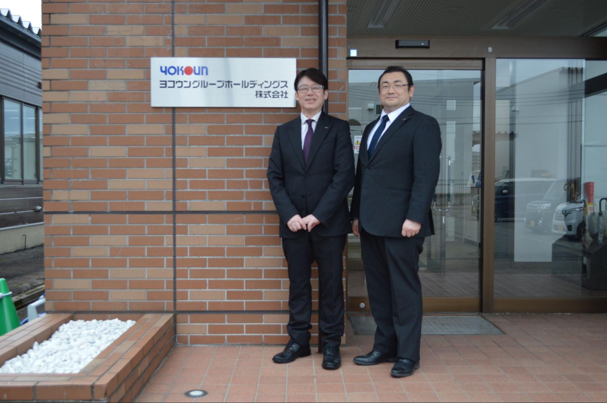 本社前に立つ塩田充弘CEO㊧と塩田聡COO