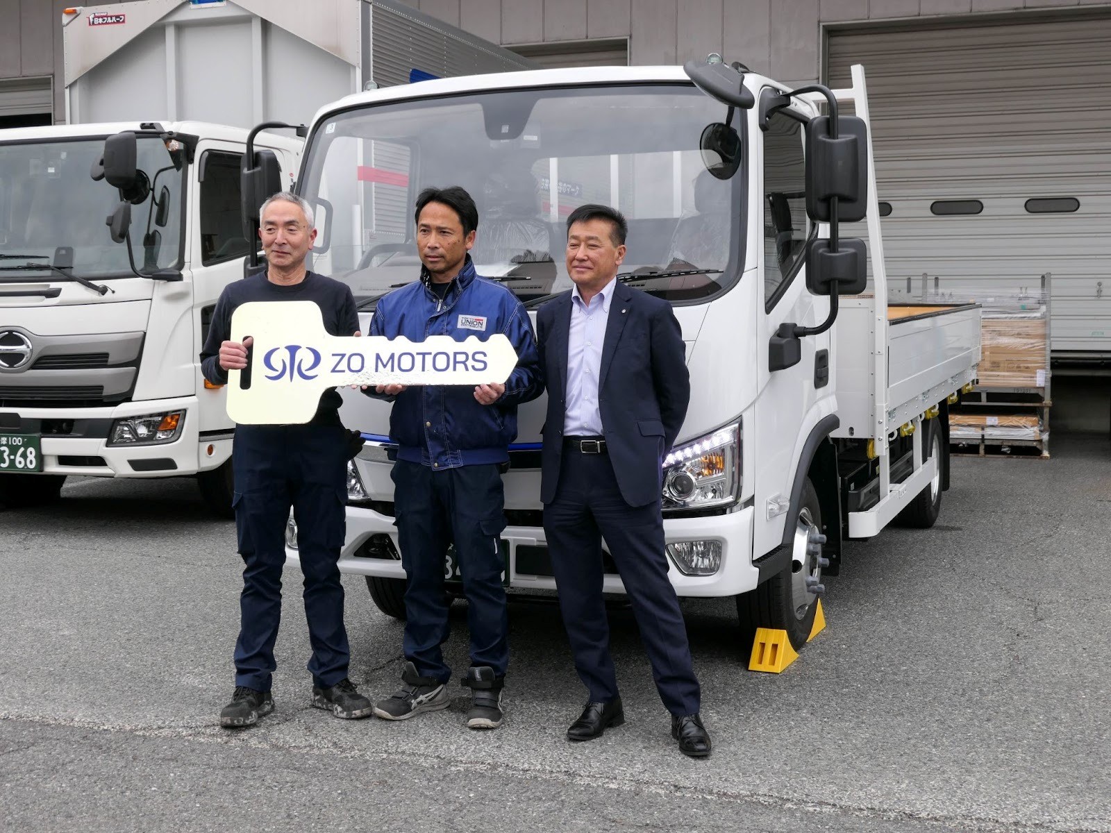 導入したトラックの前で川﨑社長（右端）と担当ドライバーら