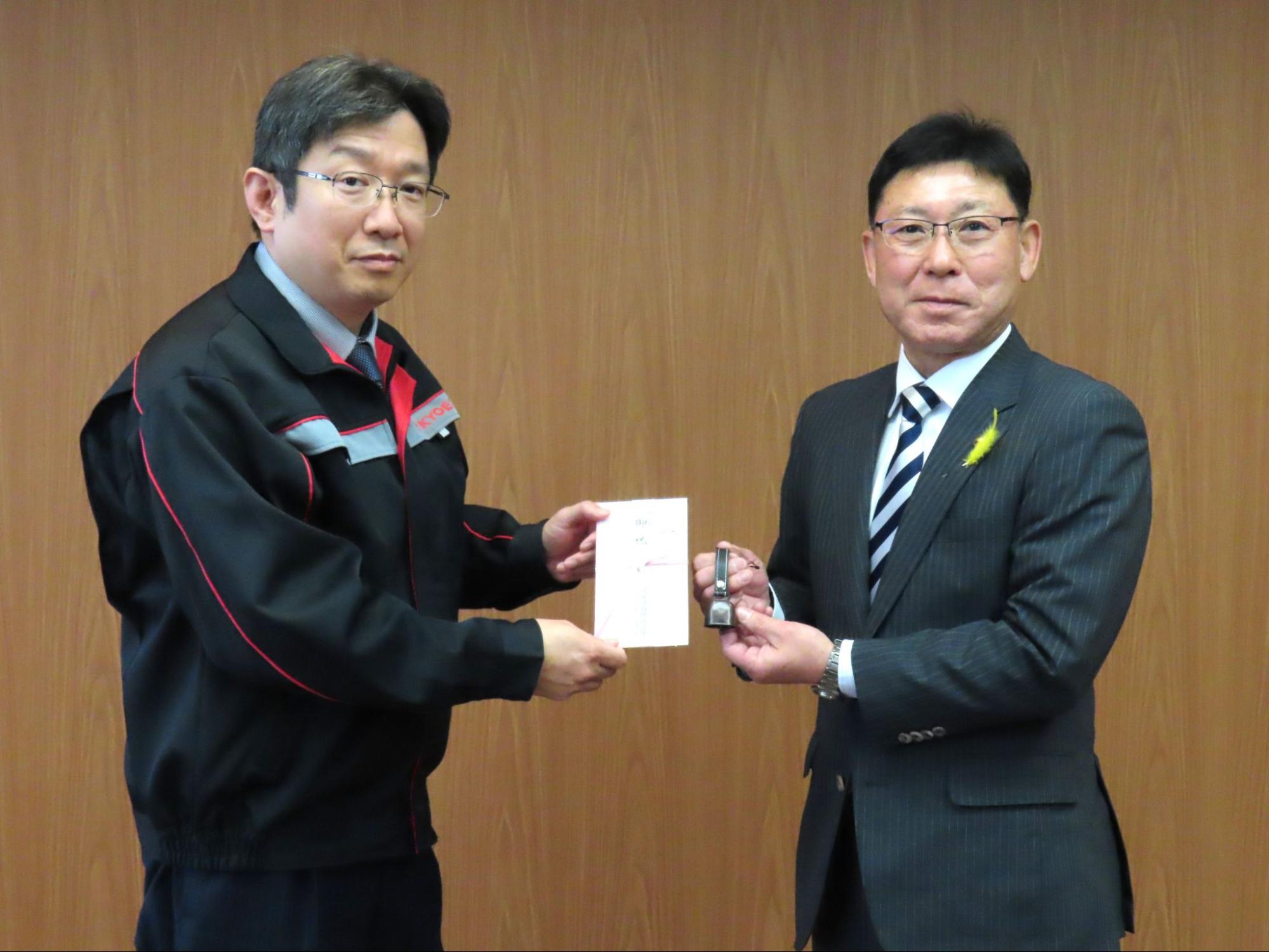 目録を持つ加藤社長とクマ鈴を持つ高橋町長