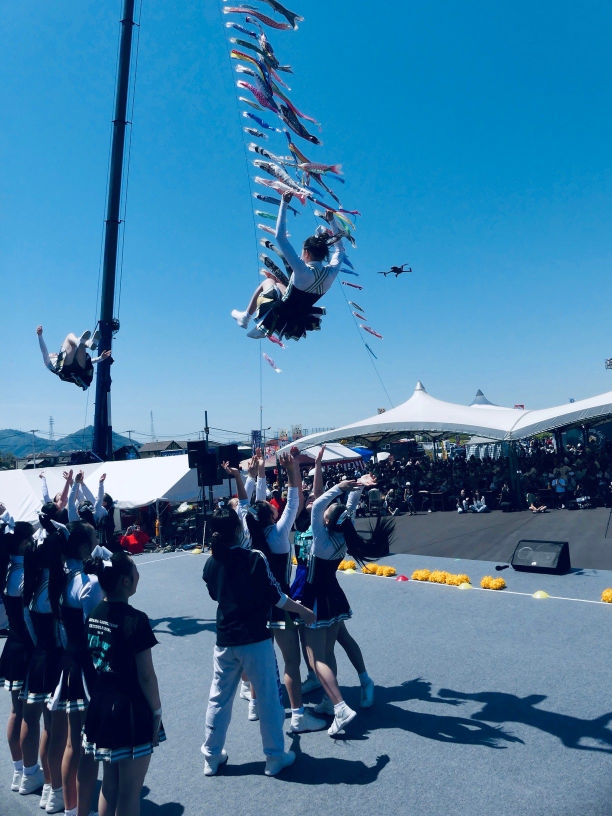 コイのぼりをバックにジャンプ技を披露する岡山学芸館高校チアリーディング部の選手