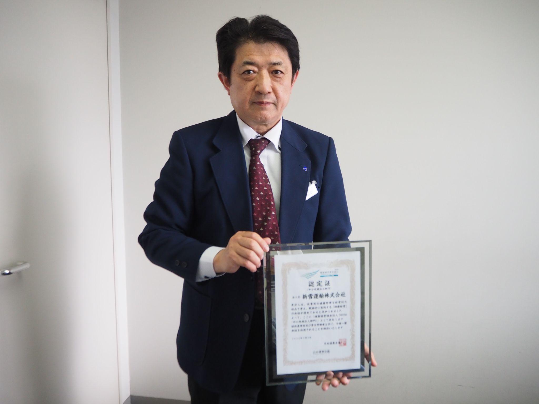 健康経営優良法人の認定証を持つ人事担当の石田英昭氏