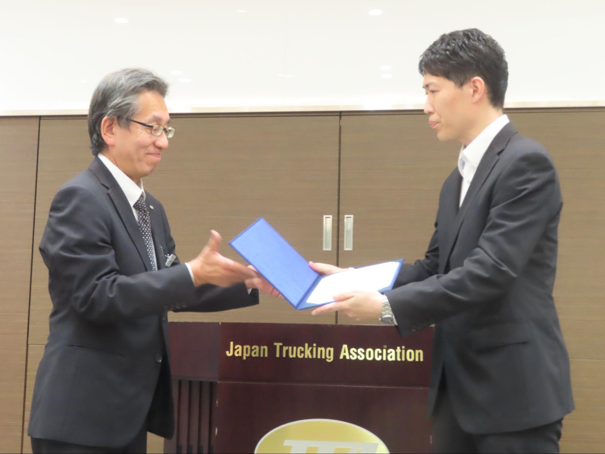 全ト協の土屋輸送事業部長㊧に依頼書を手渡す警備局公安課の岡村ローンオフェンダー等対策室副室長