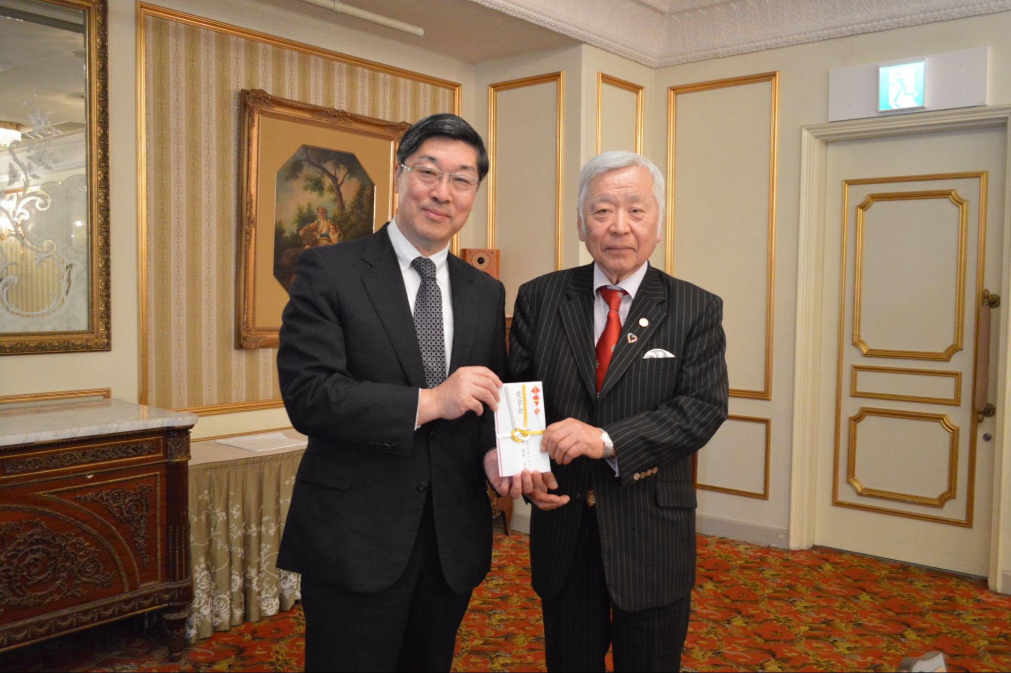 褒賞金を手に菅原理事長㊧と大須賀理事
