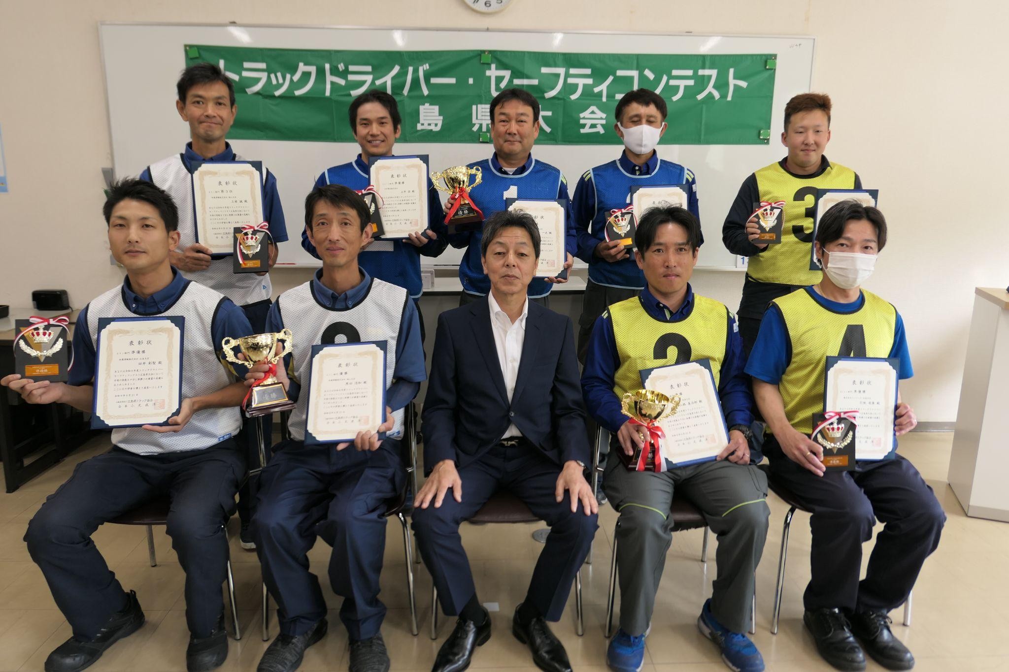表彰状を手に入賞者、三宅尊文常務