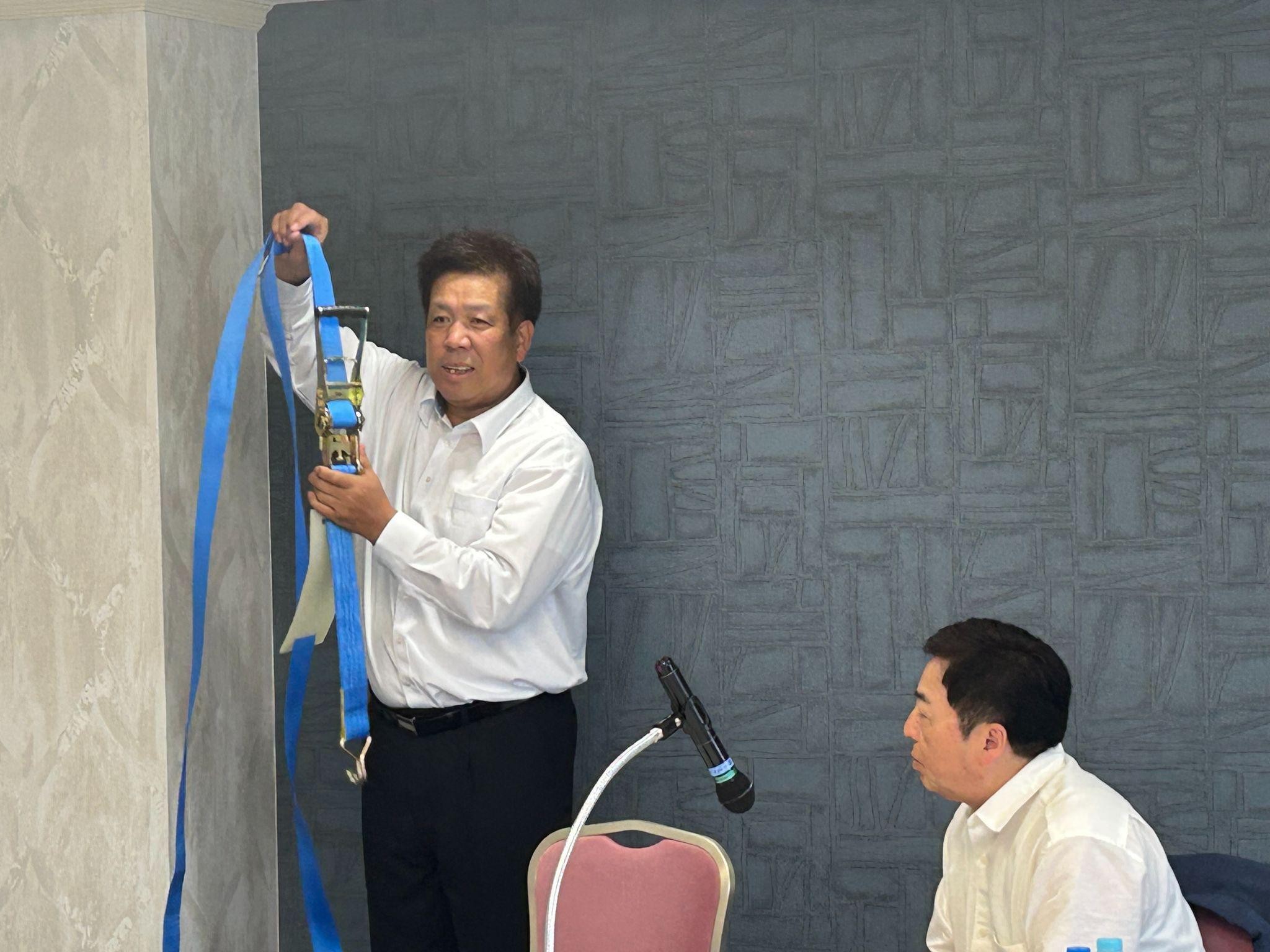 ラッシングベルトを手に安全性や操作性を説明するJL東海北陸本部平車重量部会の伊藤部会長