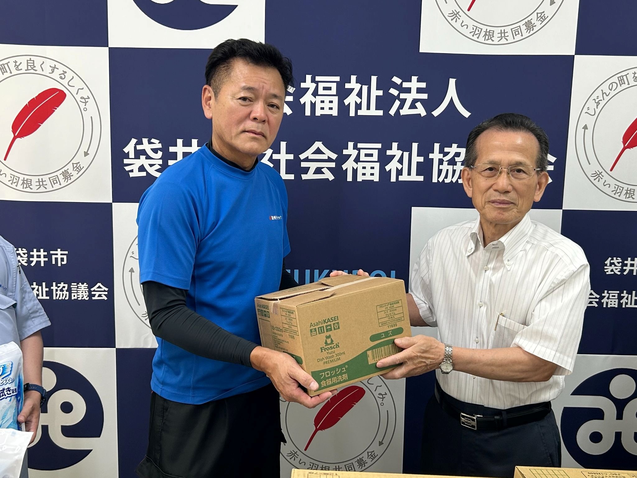 袋井市社協の池野会長㊨に寄贈品の一部を手渡す友の会の堀内会長