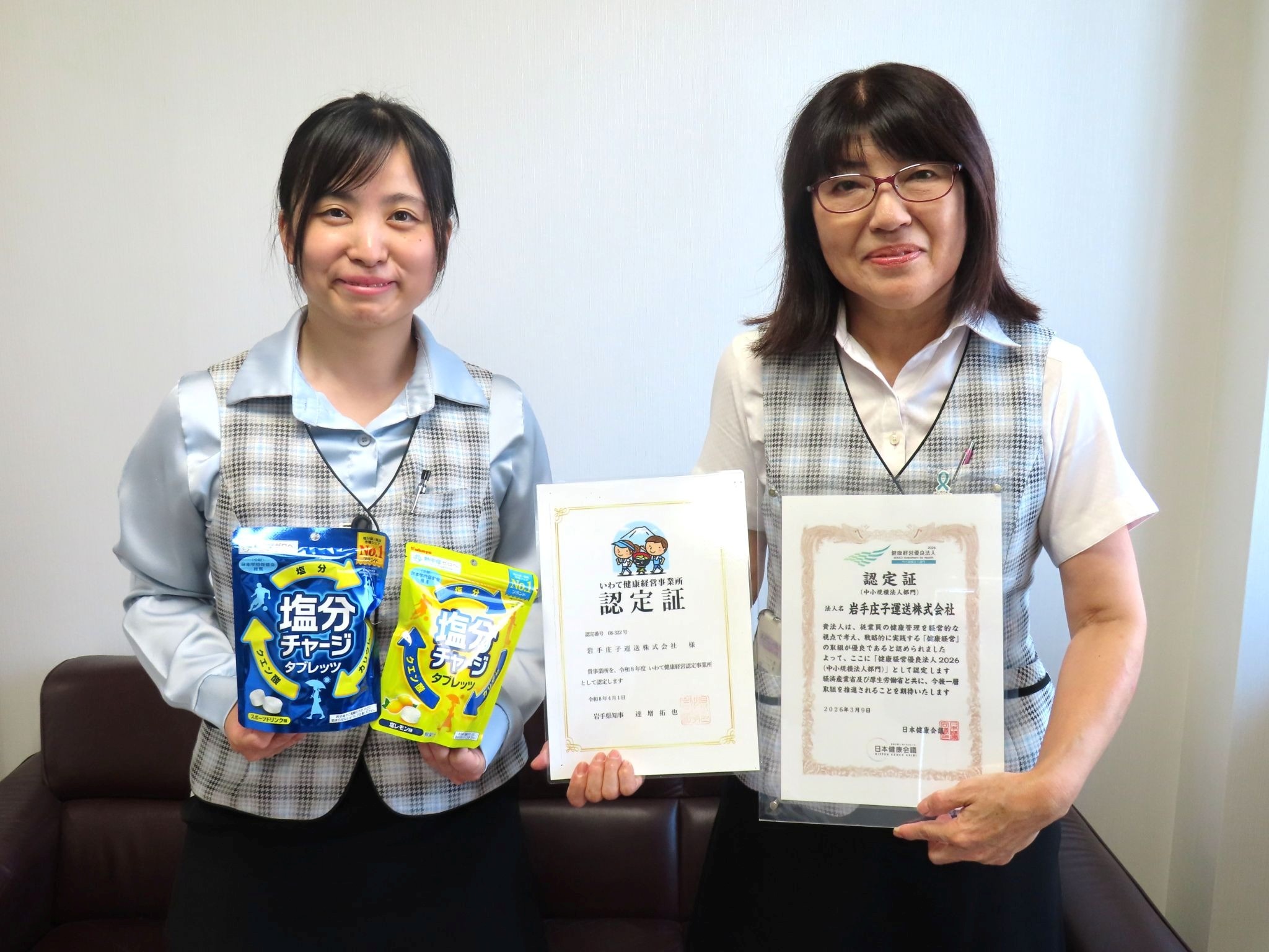 健康経営優良法人の認定証などを持つ白澤常務㊨と塩分タブレットを持つ石山氏