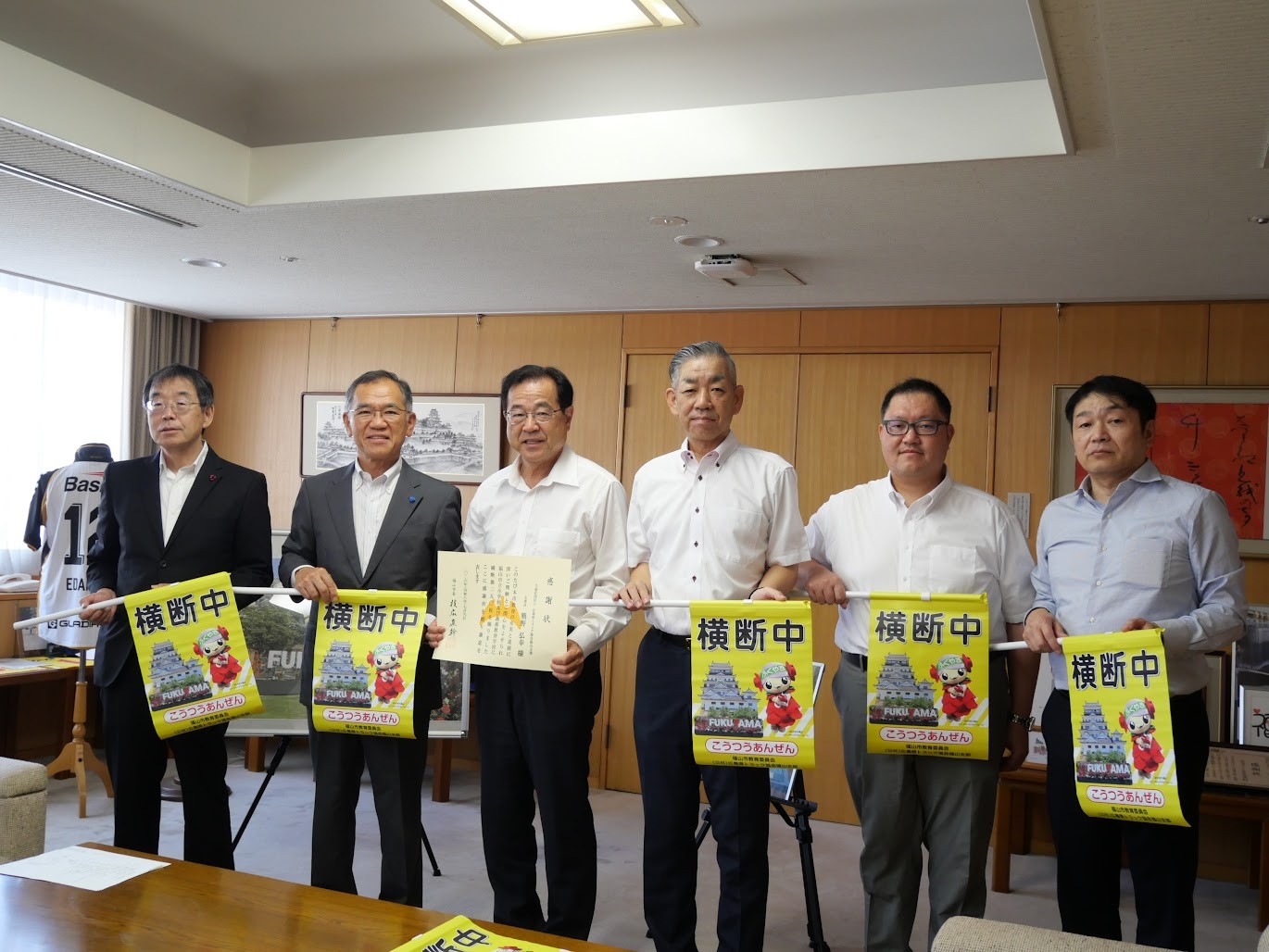 横断旗を手に枝広市長（左から2人目）と感謝状を持つ武津副支部長（右隣）ら
