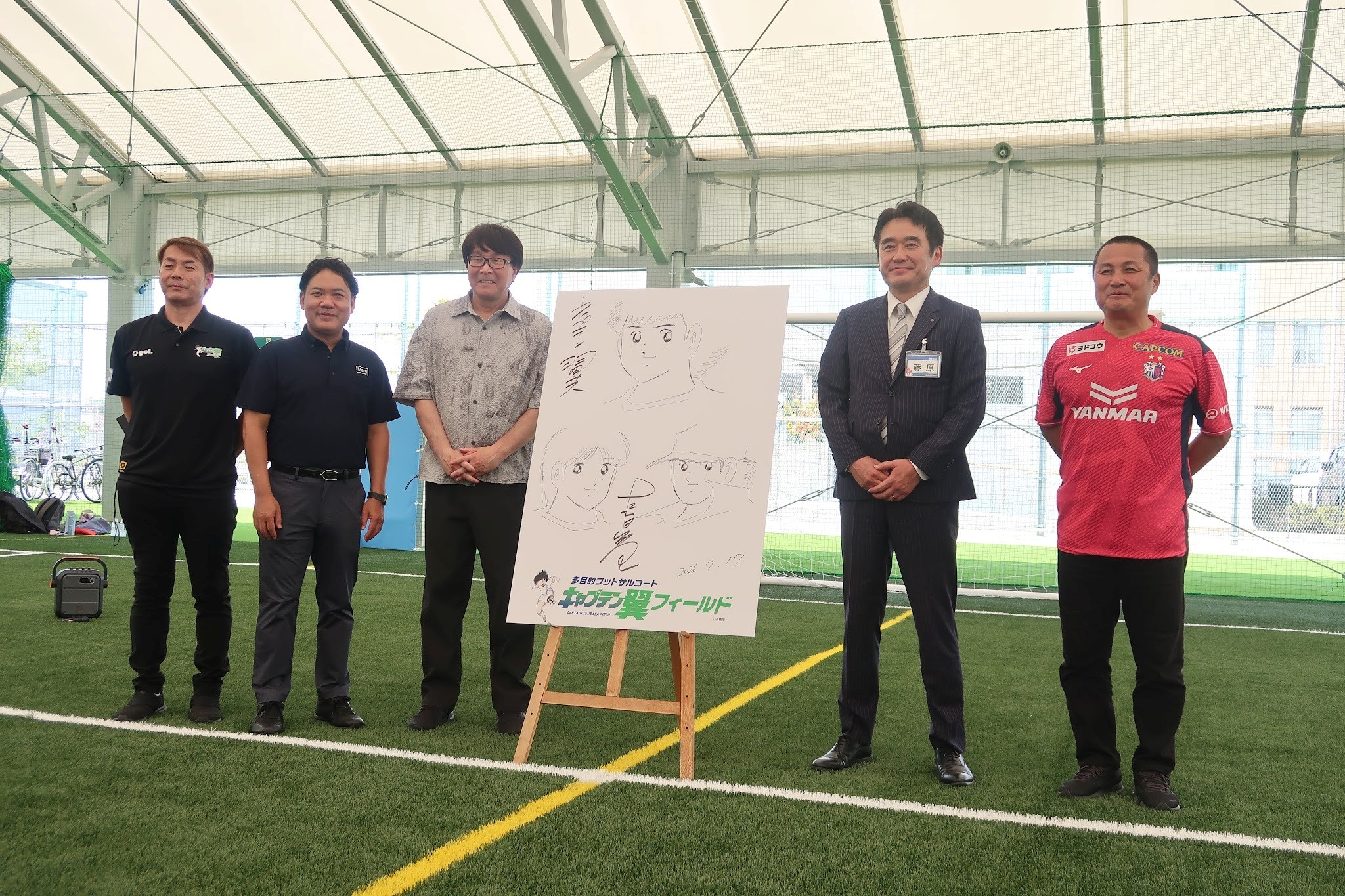 イラストと共に（左から）タディの田尻社長、GLPの三浦COO、「キャプテン翼」原作者の高橋氏、藤原東住吉区長、セレッソ大阪の森島会長