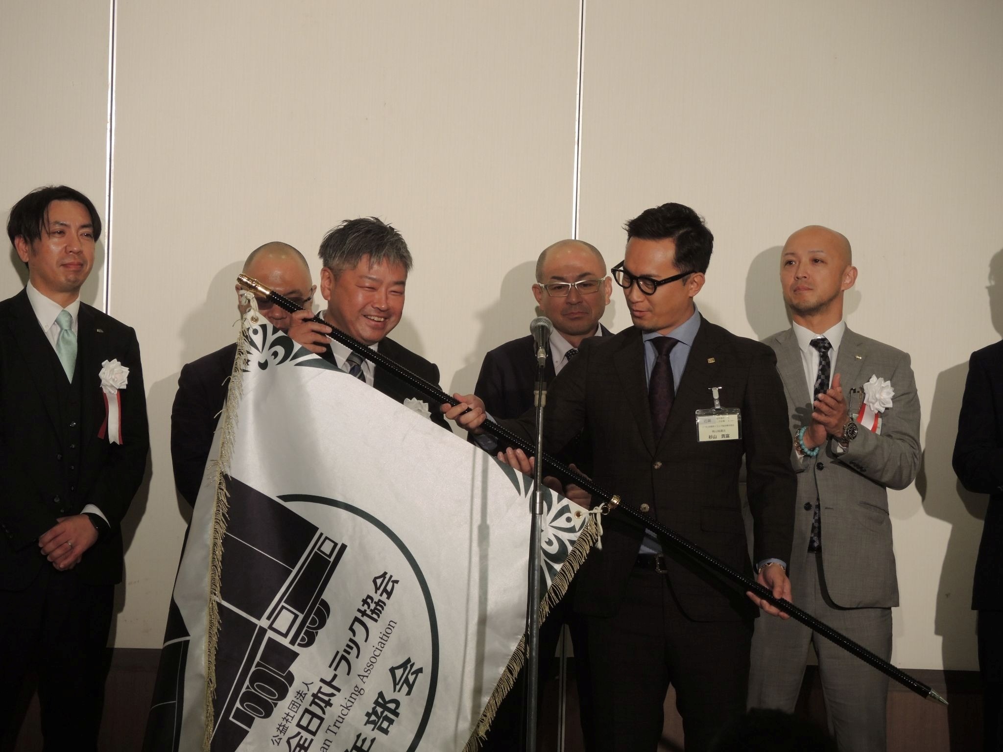 大会旗を持つ白間青連協会長㊧と杉山KTS会長