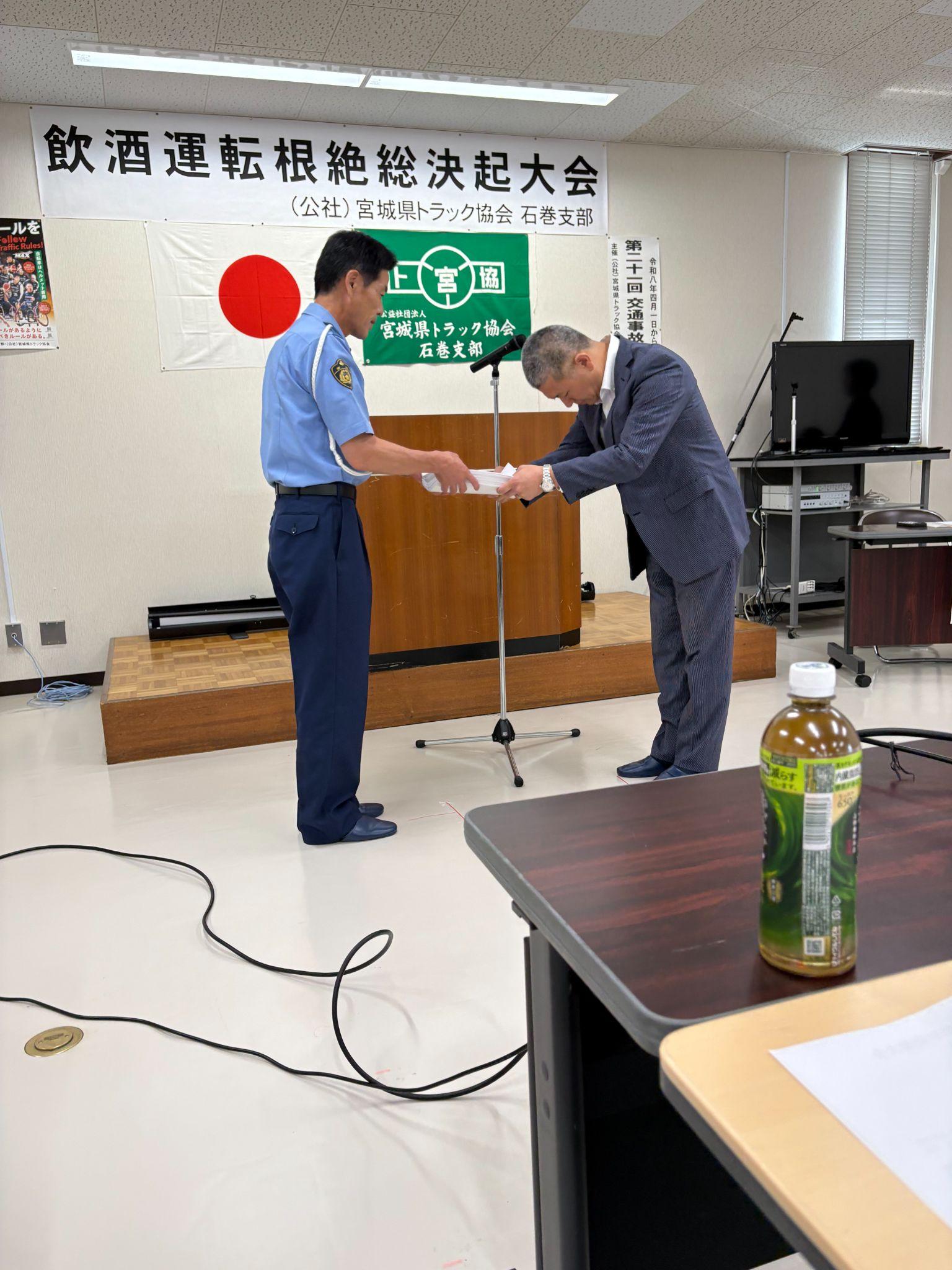 石巻署の鈴木署長㊧に誓約書と署名簿を手渡す武山支部長