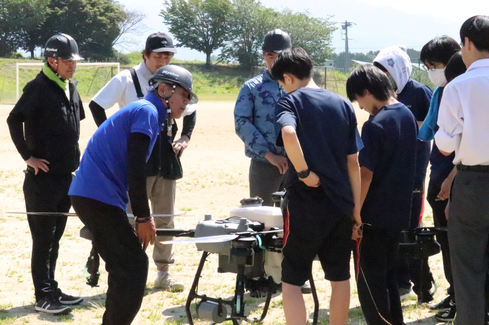 生徒に機体の構造を説明するドローン操縦士の福澤健二統括マネージャー（手前左端）