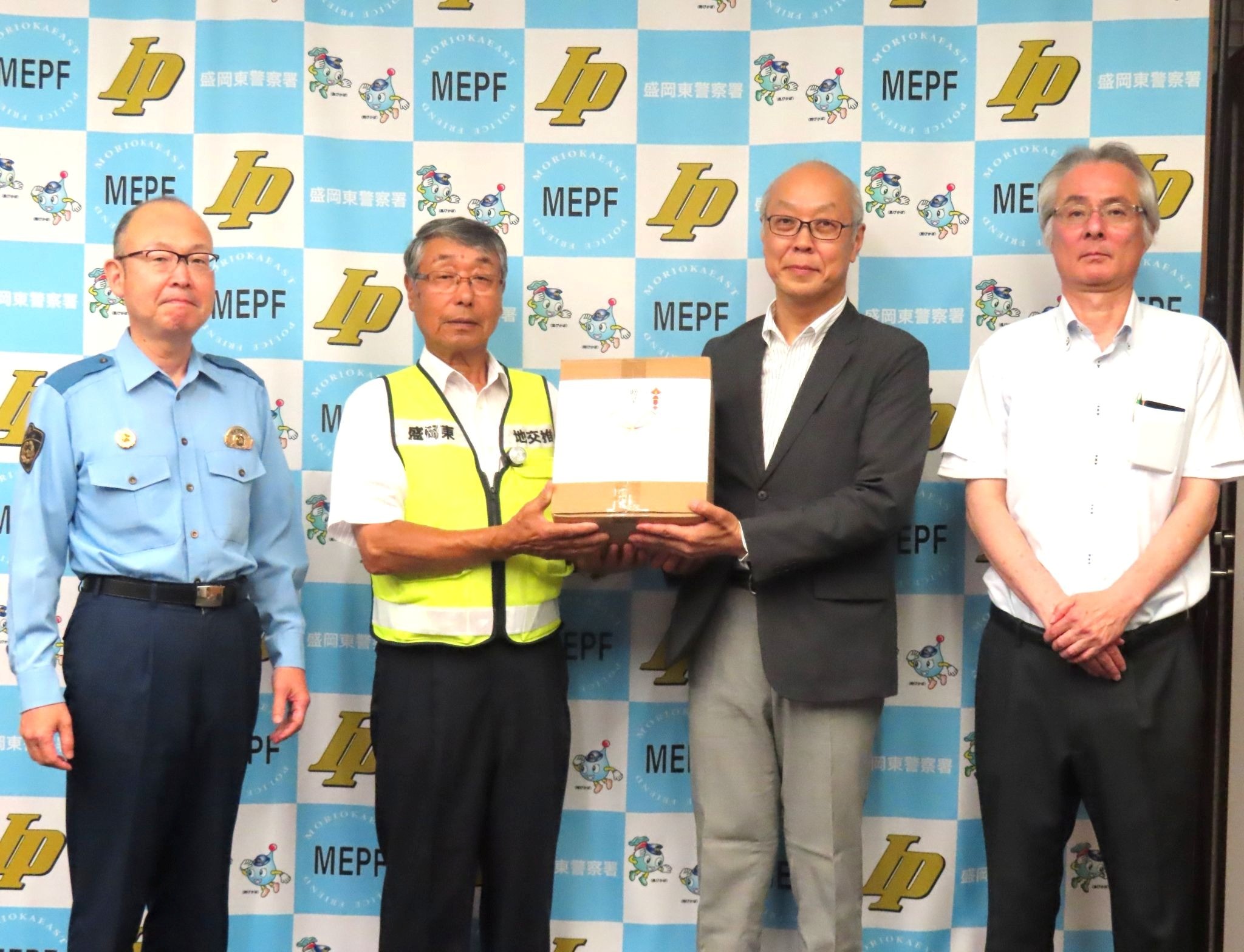 LEDクリップライトを持つ藤原支部長㊨と地域交通安全活動推進委員協議会の熊谷会長ら