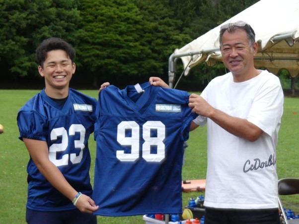 ウエアを持つ伊藤社長㊨と北海学園大アメフト部の齊藤主将