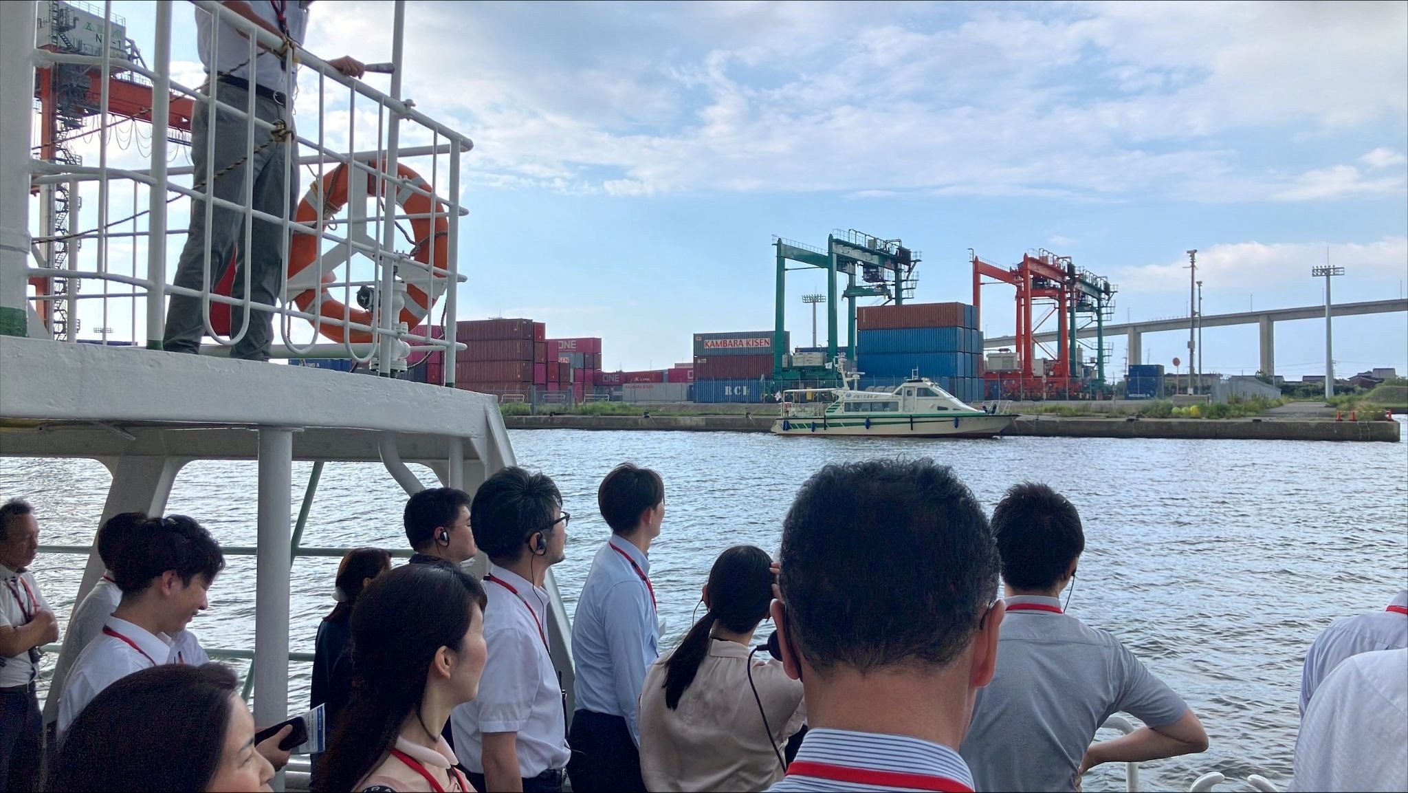 視察艇から港湾の風景を眺める参加者ら