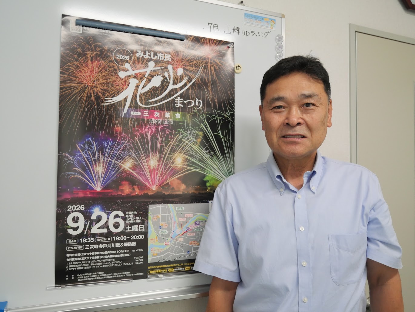 みよし市民花火まつりのポスターの前で細川社長