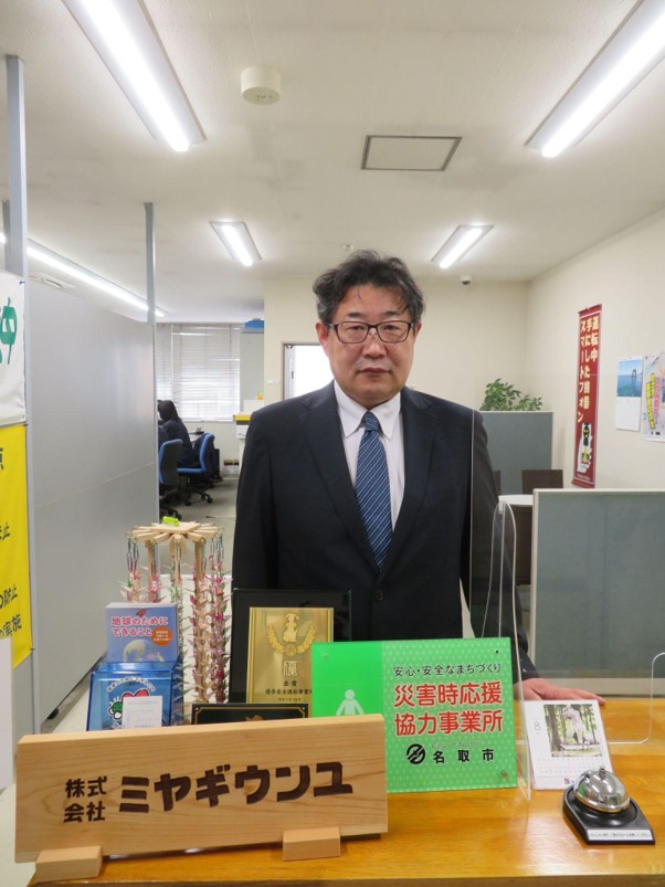 協定のプレートを前に鈴木社長