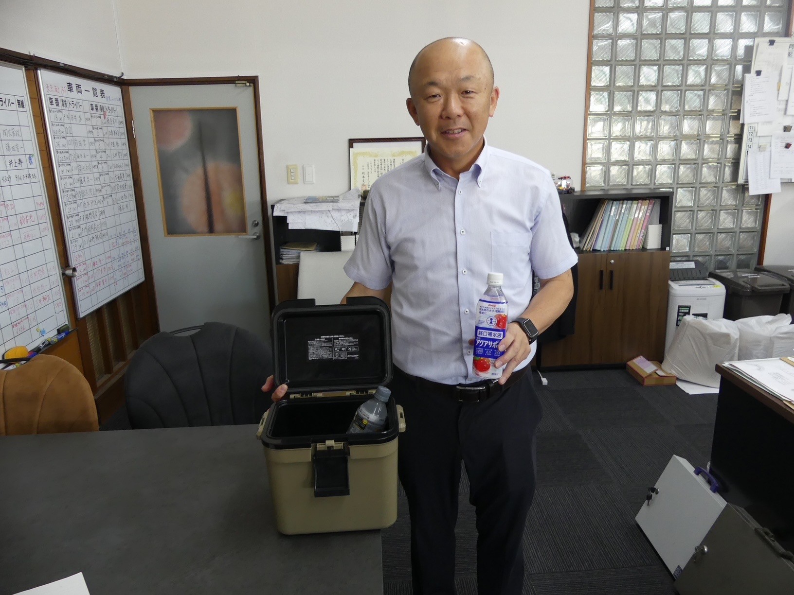 クーラーボックスと経口補水液を手に大平社長