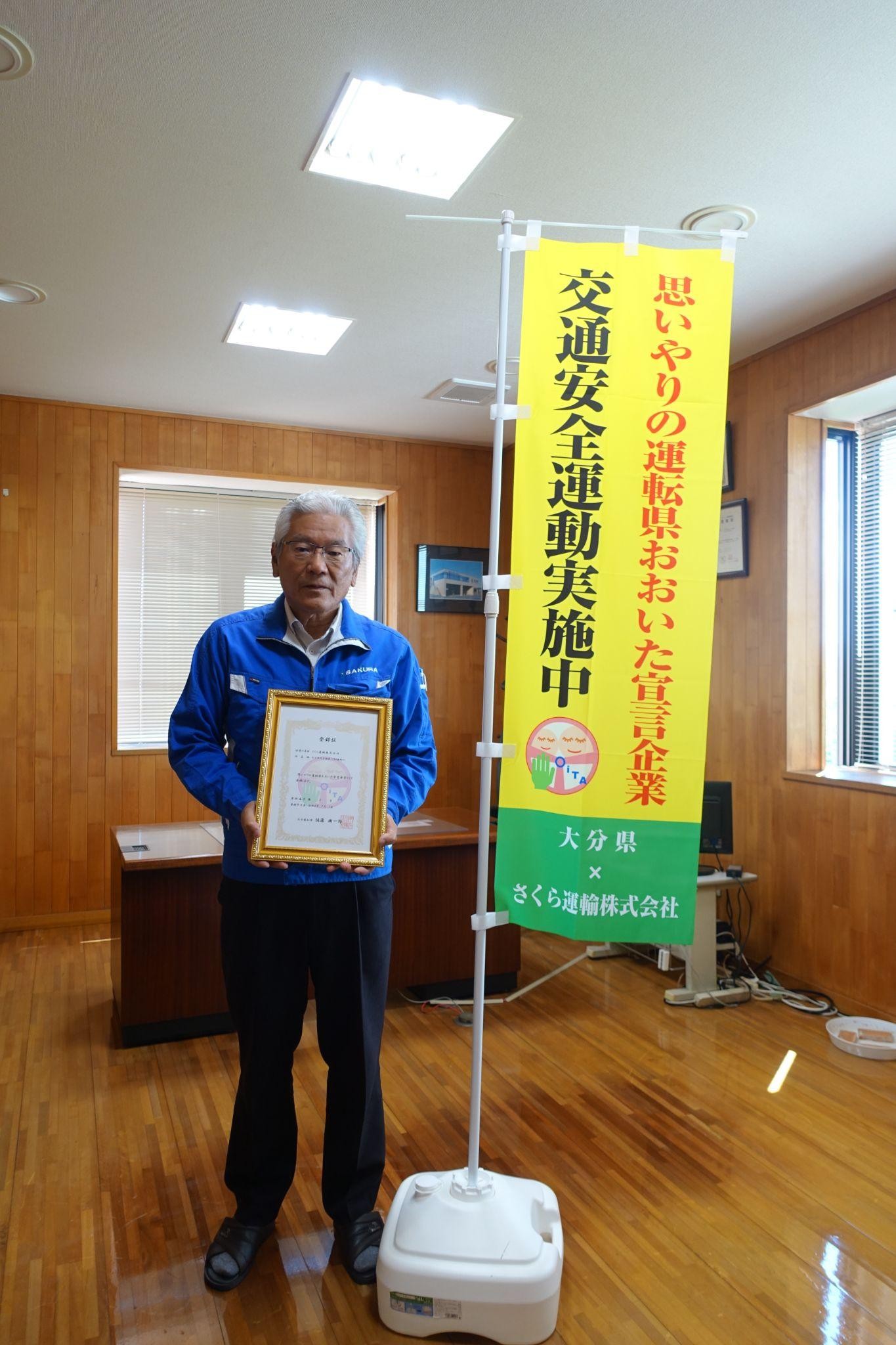 思いやりの運転県おおいた宣言企業の登録証を手に後藤社長