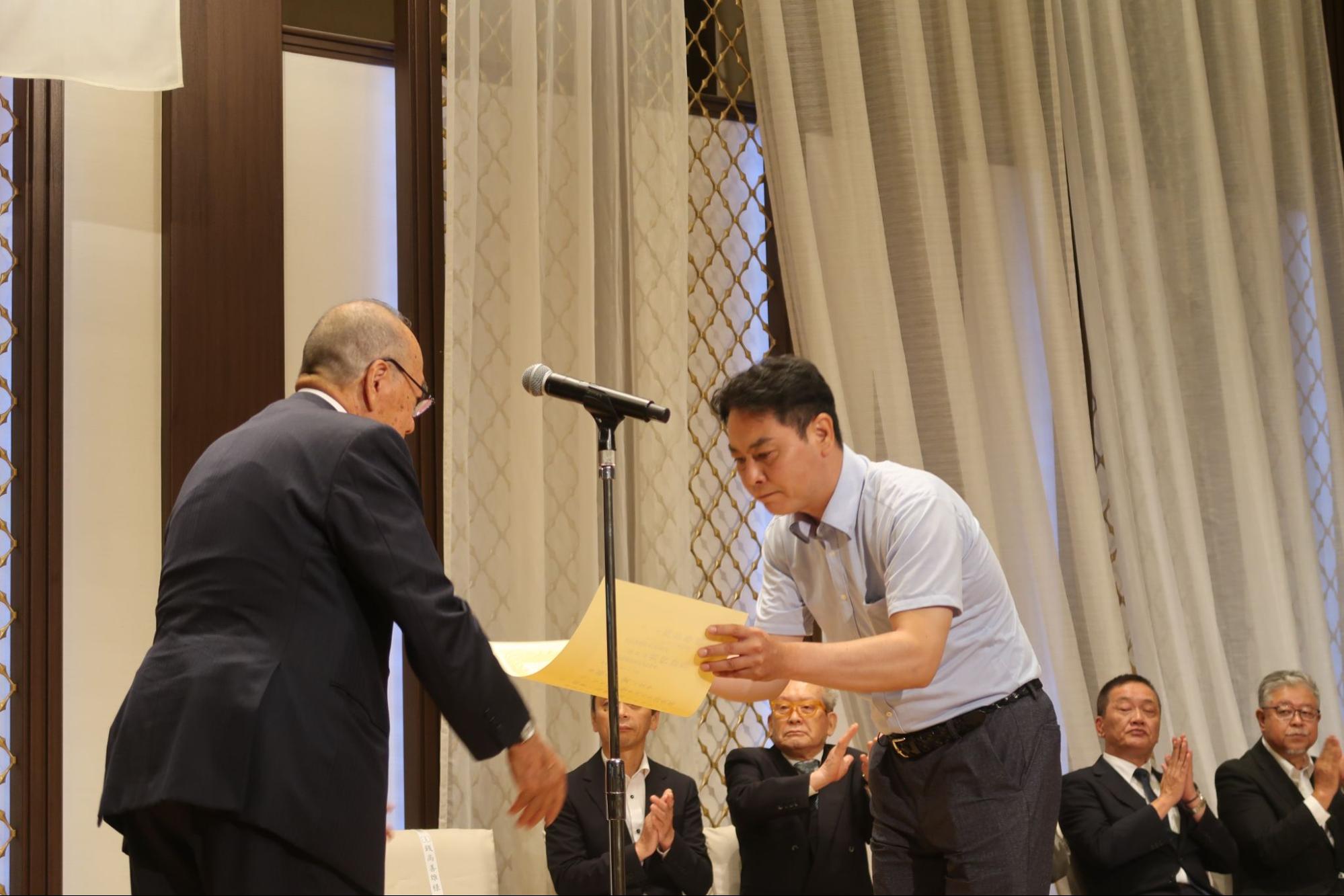 受賞した事業所の代表者に表彰状を授与する銭高会長㊧<br>