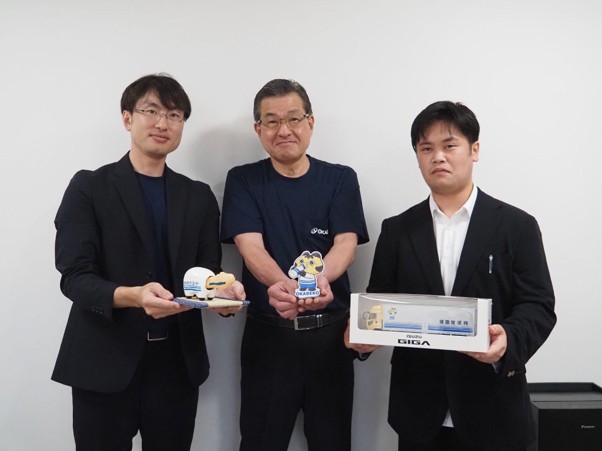 OKABEKOくんグッズを手に（左から）割谷常務、割谷社長、石川晴彦人事課長代行