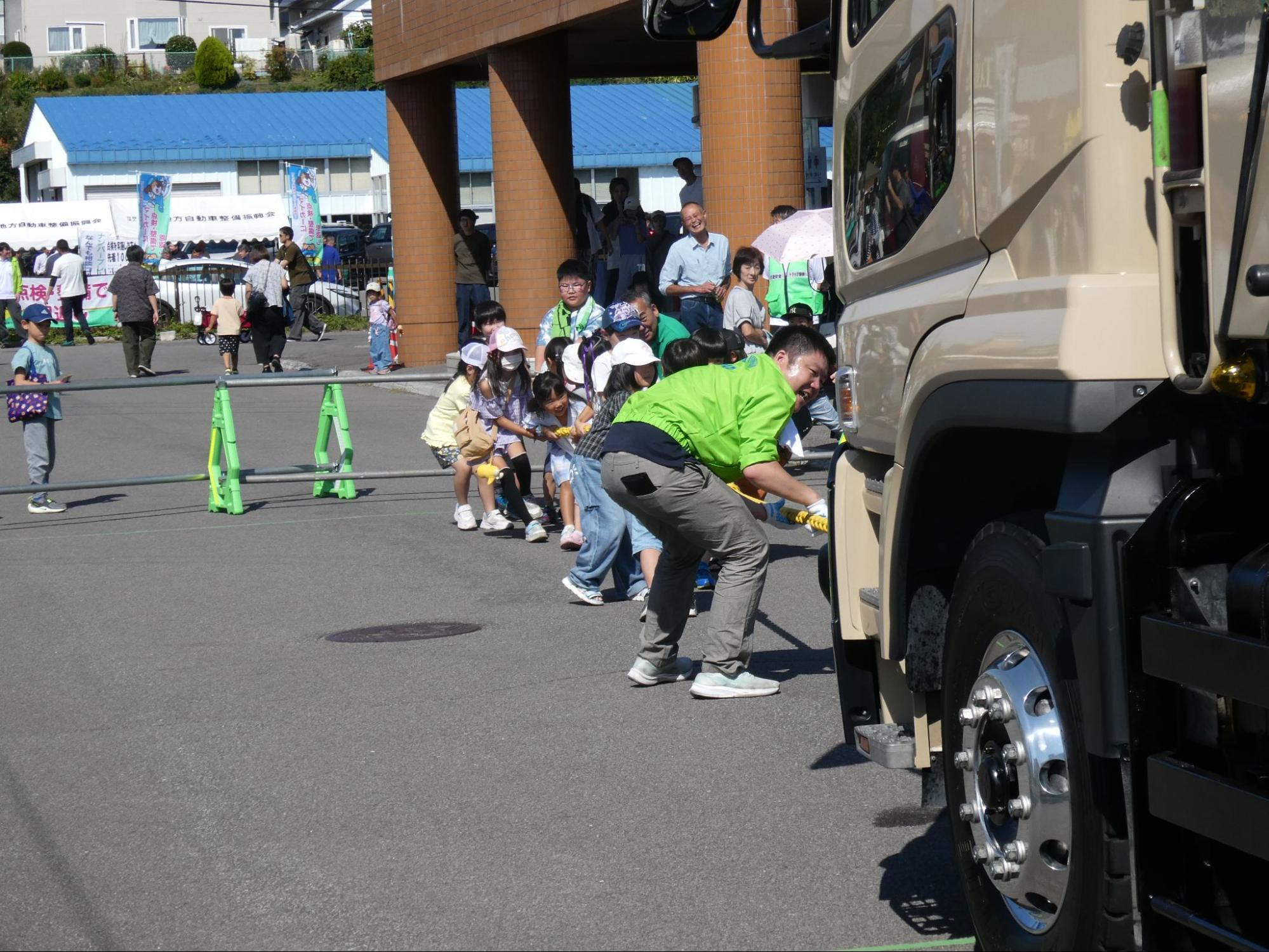 大型ダンプトラックと子どもたちの綱引き