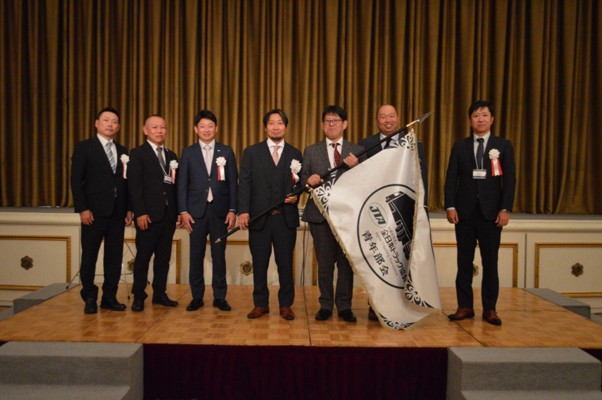 大会旗を手にする門馬会長（中央）と中部B青年協の佐藤代表幹事（右隣）