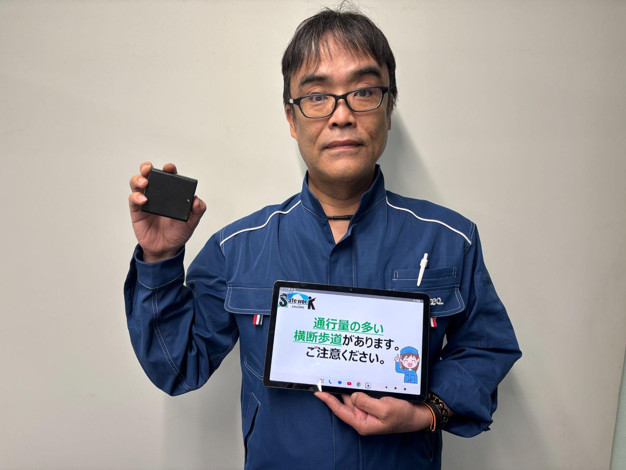 タブレットとビーコンを手に持つ黒田所長